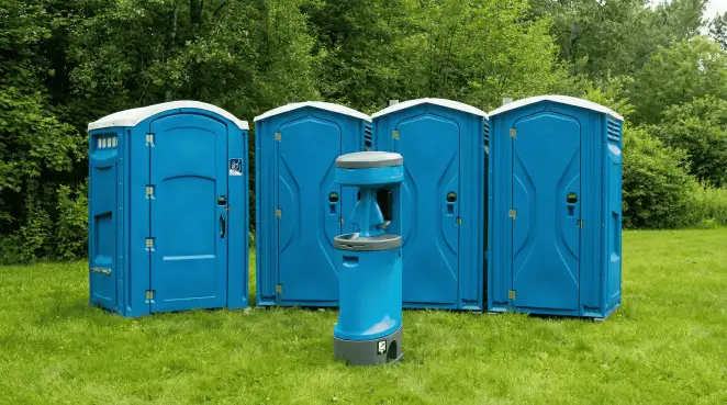 Four blue portable toilets and a matching hand washing station on grass near trees, a common sight at local outdoor events in Naperville, IL